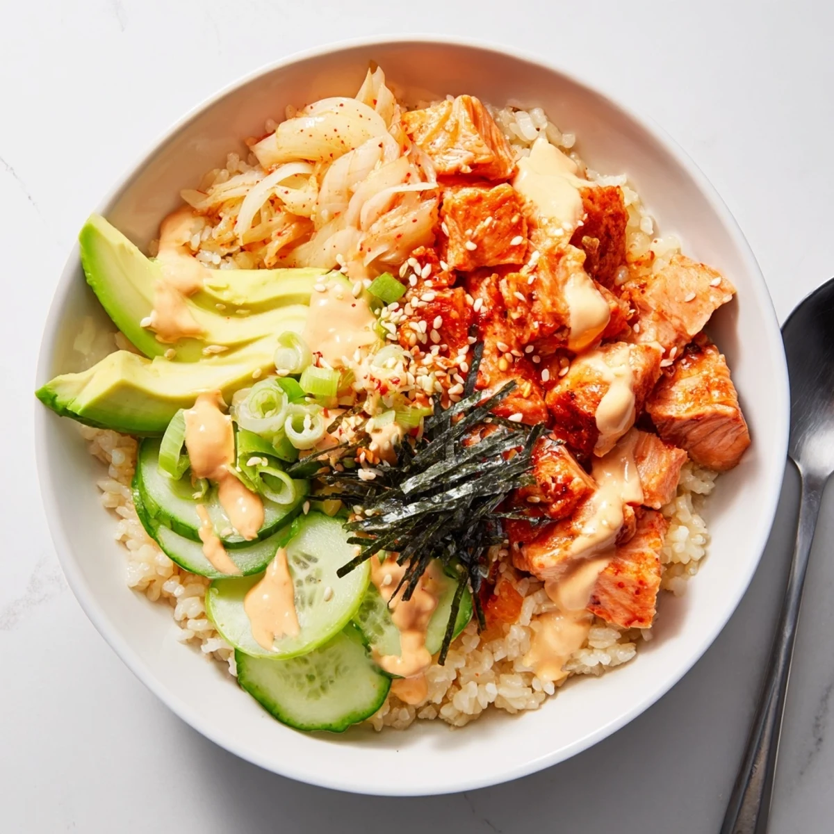 Crispy salmon rice bowl topped with spicy mayo, kimchi, and fresh avocado slices.  