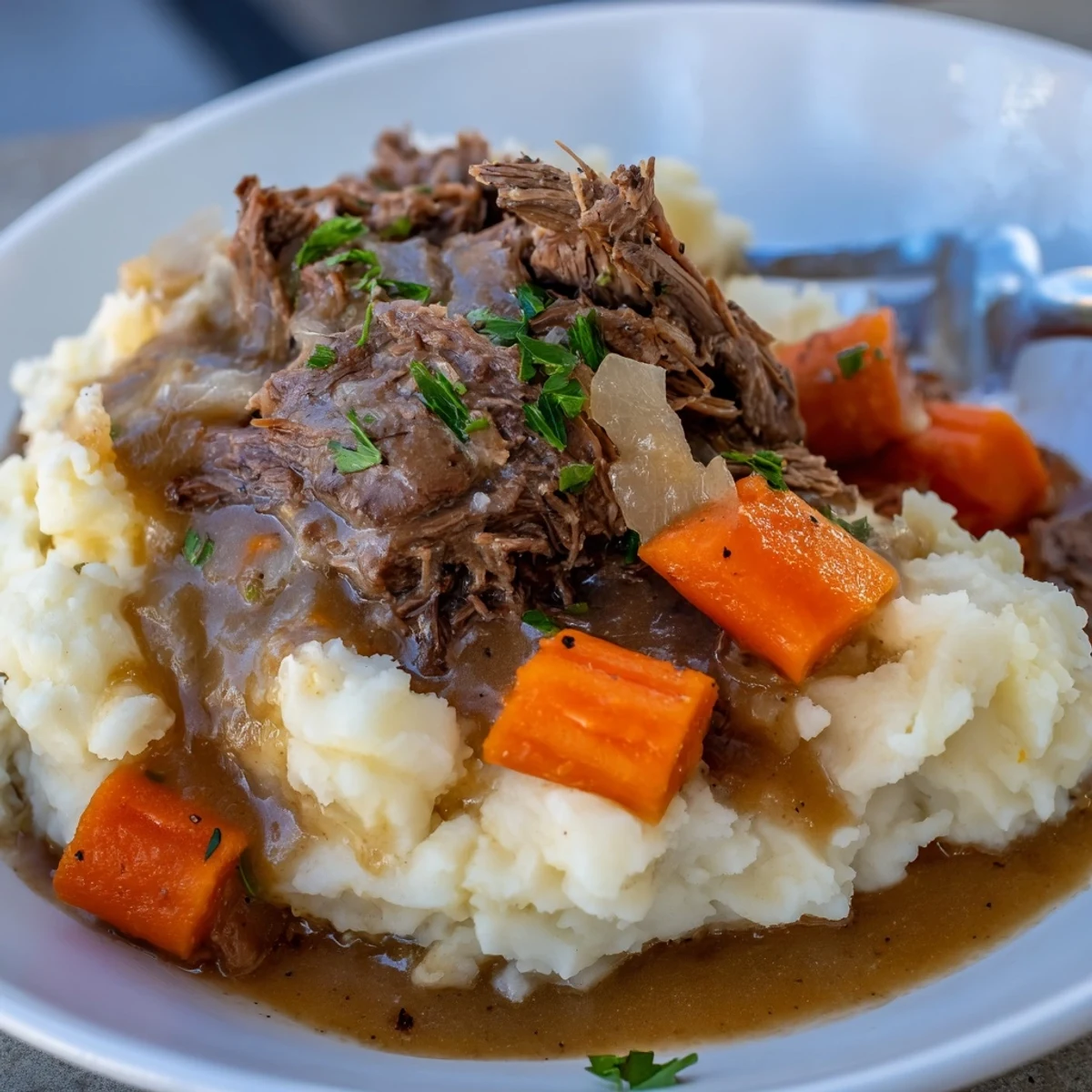Tender beef roast drenched in rich gravy, resting on creamy mashed potatoes.