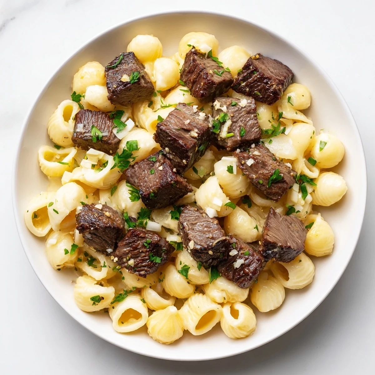 Golden brown Garlic Butter Steak Bites, aromatic with garlic, served with a cheesy pasta side.