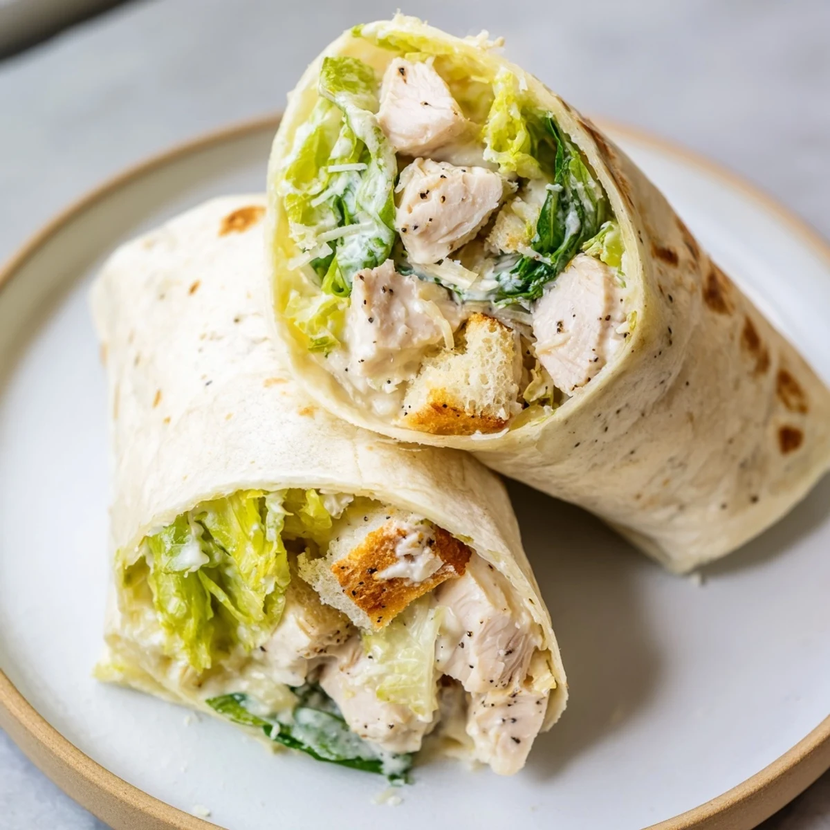 Chicken Caesar Wraps with juicy chicken and creamy Caesar dressing, ready to eat rolled up.