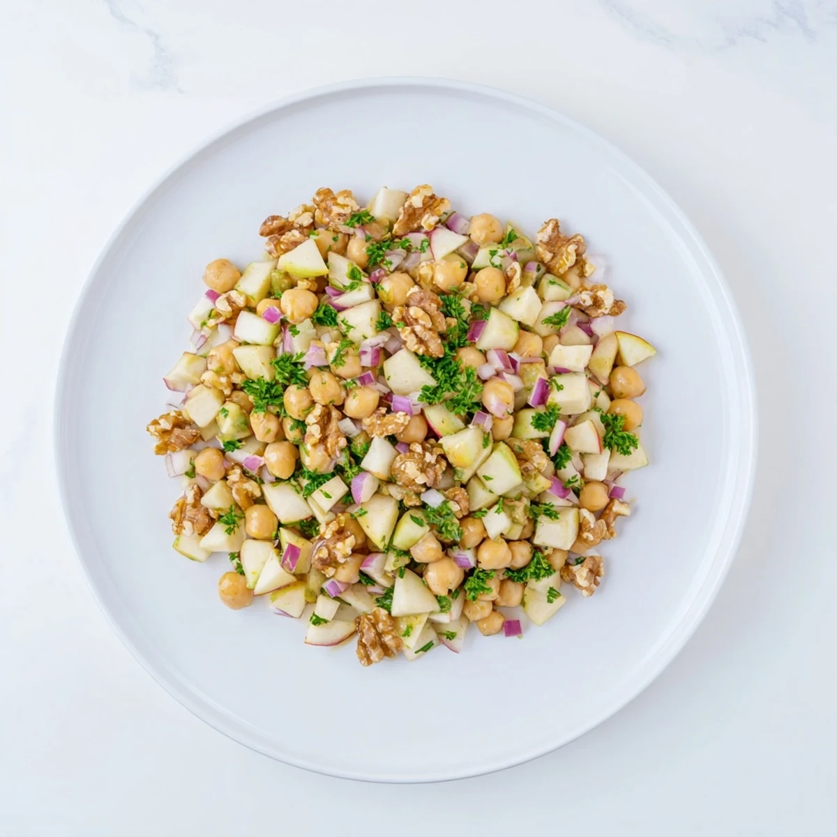 Fall Harvest Apple and Chickpea Salad: A colorful mix of apple pieces, chickpeas, and walnuts glistening with dressing.