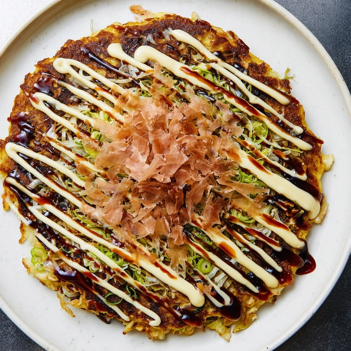 Golden-brown Japanese okonomiyaki pancakes, with visible shredded cabbage and savory sauce drizzle.
