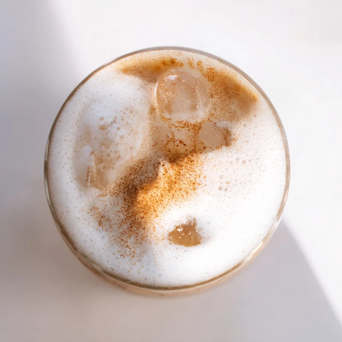 A close-up of Iced Chai Tea with cold foam shows the perfect layered drink, ready to sip.