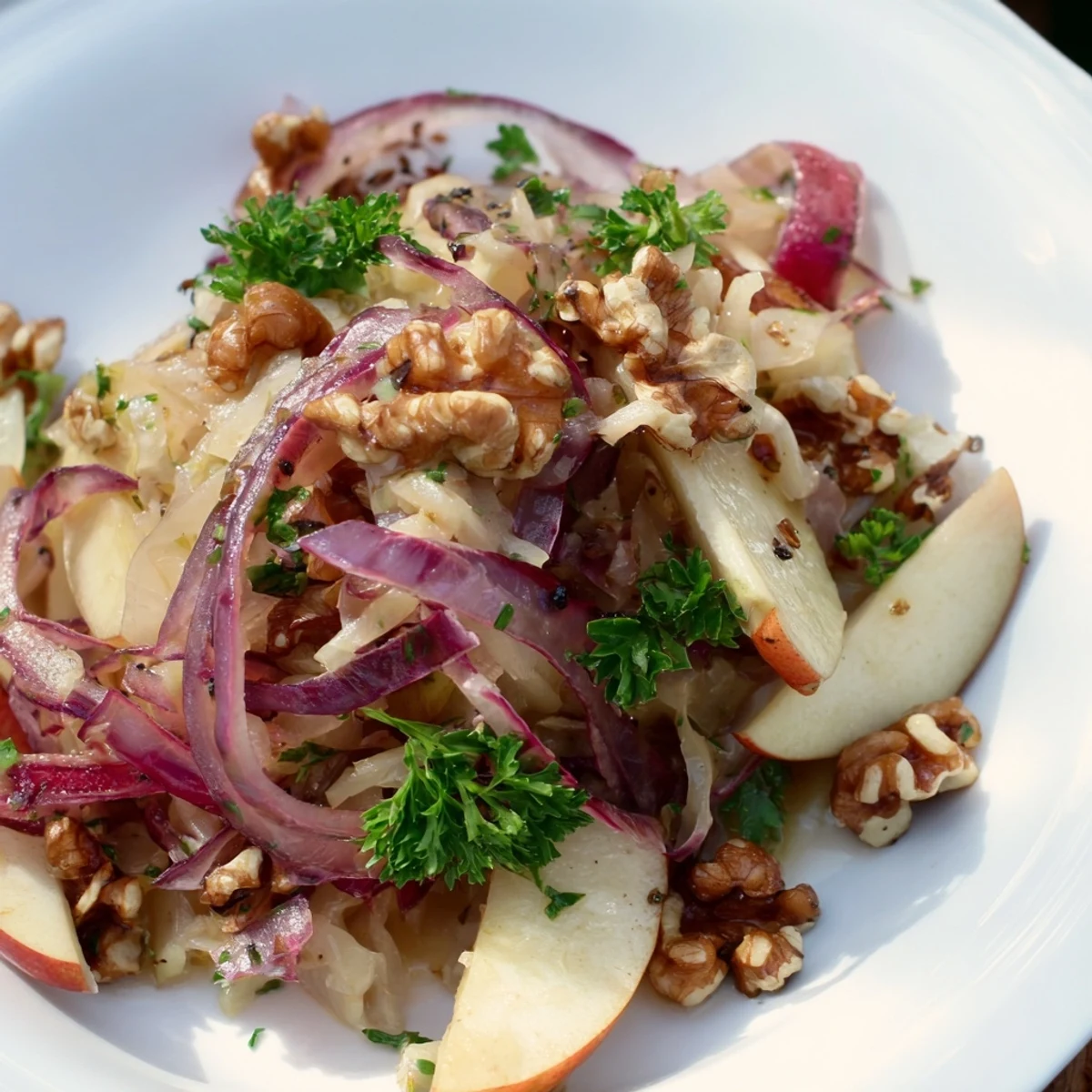 A warm Apple and Sauerkraut Skillet Salad with caramelized apples, red onions, and fresh parsley garnish on a serving platter.
