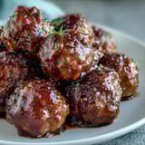Glossy Easy Sweet and Sour Crock Pot Meatballs simmering in a slow cooker, coated in a tangy, sticky apricot sauce.