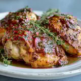 A slow cooker holds golden-brown chicken breasts coated in a velvety honey mustard sauce, garnished with fresh parsley.