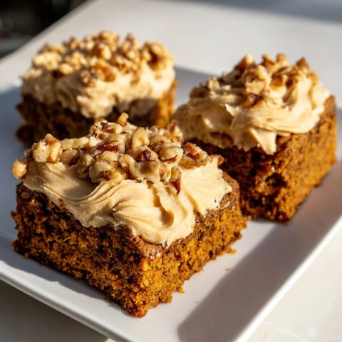Moist Pumpkin Bars with brown sugar frosting, topped with toasted nuts, ready to serve as a fall dessert.