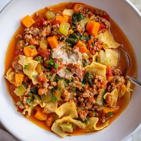 A steaming bowl of Healthy Lasagna Soup, garnished with vibrant fresh herbs and melted cheese.