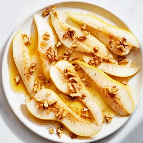 Fresh pear slices with golden honey drizzle, a simple and elegant dessert.