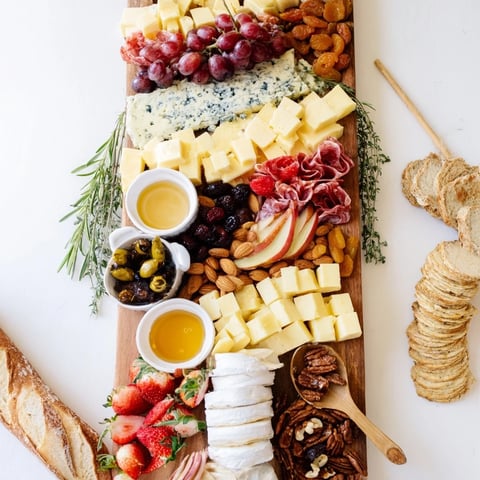 A bountiful The Waterfall Edge Grazing Board cascades with cheeses, meats, and brightly colored fruits.