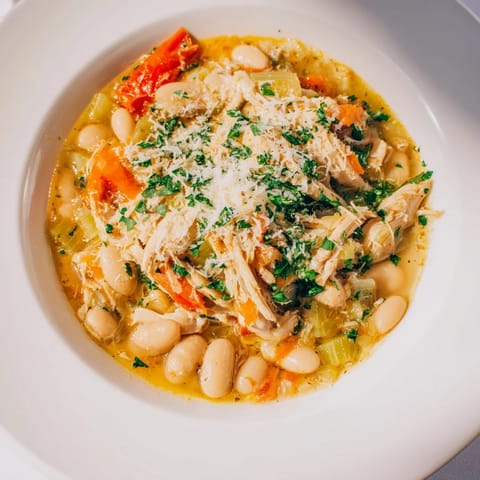 This close-up displays the hearty White Bean and Roasted Red Pepper Chicken, garnished with fresh parsley and cheese.