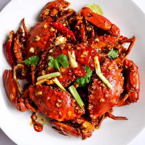 Fragrant Singaporean Chili Crab: a close-up shows tender crab pieces covered in a vibrant, spicy sauce.