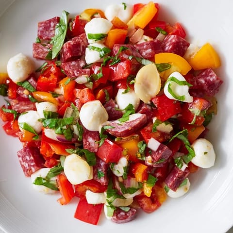 Bright Italian-inspired Crunchy Antipasto Chopped Salad with pepperoncini, olives, tomatoes, and cucumbers, garnished with fresh parsley and basil on a rustic table.