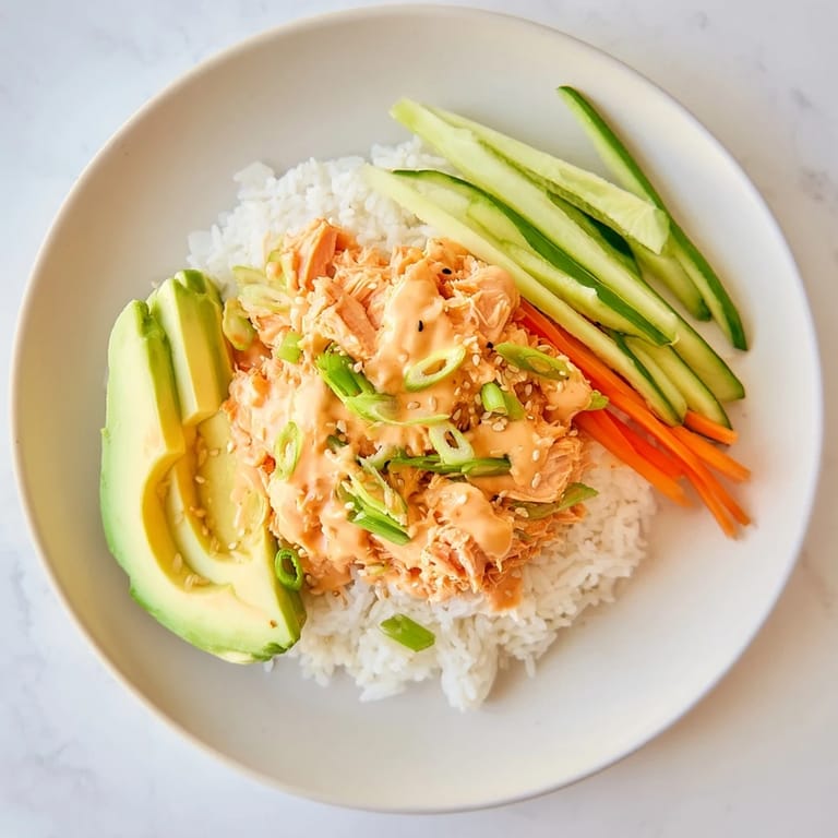 Steaming Spicy Canned Salmon Rice Bowl, with flaked salmon, bright vegetables, and a spicy mayo drizzle.