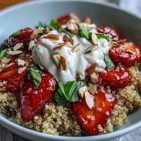 A vibrant Strawberry Basil Breakfast Quinoa Bowl topped with sliced strawberries and fresh basil, drizzled with vegan honey.