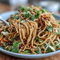 Asian Sesame Noodle Salad with Peanut Dressing served in a large bowl, garnished with cilantro and sesame seeds.  