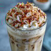 Creamy Vanilla Bean Coconut Frappuccino Mocktail with frothy coconut milk and real vanilla bean seeds, served over ice in a tall glass.
