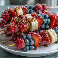 Festive red, white, and blue fruit skewers with strawberries, bananas, and blueberries, perfect for Fourth of July celebrations.